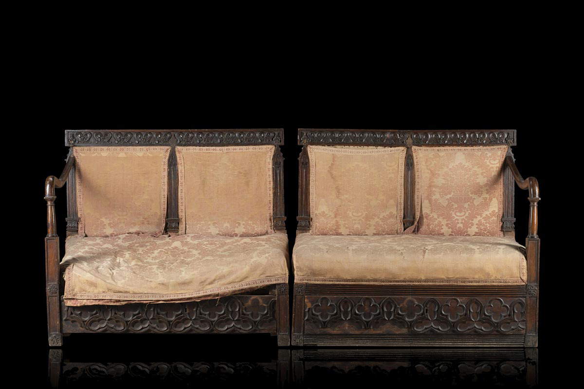 Coppia di panchetti in stile neogotico intagliati a rosoni con braccioli mossi, rivestiti in stoffa originale (103 x 93 x 58 cm ciascuno)