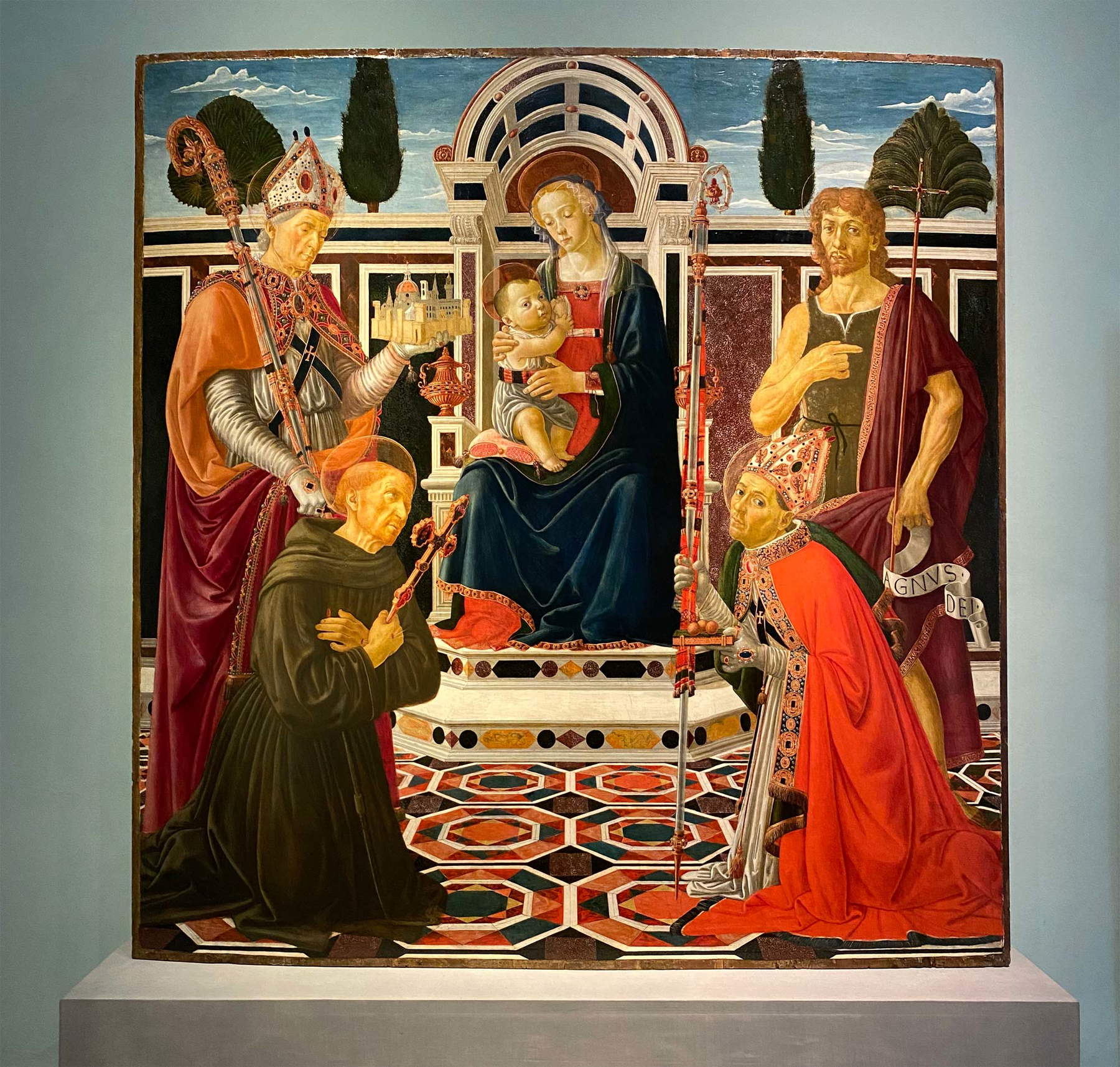 Andrea del Verrocchio y taller, Conversación sagrada con los santos Zanobi, Francisco, Juan Bautista y Nicolás conocida como Retablo Macinghi (1472; técnica mixta sobre tabla, 176 x 170,4; Florencia, Galería de los Uffizi, Galería de Estatuas y Pinturas, inv. 1890, n.º 1592, en depósito fuera de la iglesia de San Martino a Strada) Andrea del Verrocchio y taller, Conversación sagrada con los santos Zanobi, Francisco, Juan Bautista y Nicolás conocida como Retablo Macinghi (1472; técnica mixta sobre tabla, 176 x 170,4; Florencia, Galería de los Uffizi, Galería de Estatuas y Pinturas, inv. 1890, n.º 1592, en depósito fuera de la iglesia de San Martino a Strada)