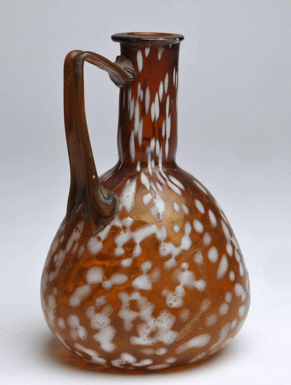 Cruche piriforme à une anse avec décor appliqué à points blancs (de Scaldasole ; milieu du Ier siècle après J.-C. ; verre soufflé ambré ; Vigevano, Museo Archeologico Nazionale della Lomellina) Cruche piriforme à une anse avec décor appliqué à points blancs (de Scaldasole ; milieu du Ier siècle après J.-C. ; verre soufflé ambré ; Vigevano, Museo Archeologico Nazionale della Lomellina)