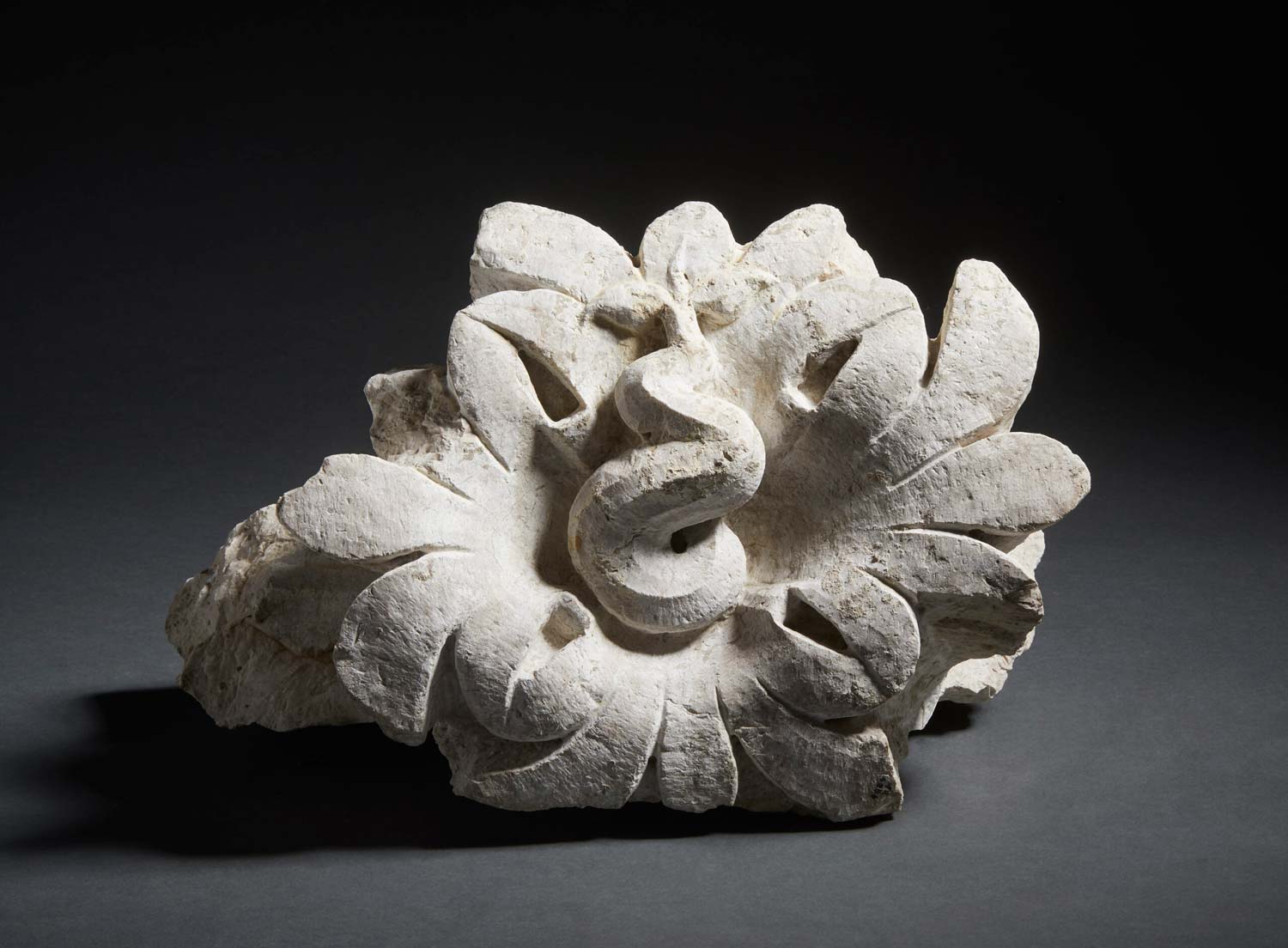 Ábaco flor de capitel con motivo serpentiforme, piedra de Botticino, segunda mitad del siglo I d.C., Archivo Fotográfico de los Museos de Brescia, Fotostudio Rapuzzi Ábaco flor de capitel con motivo serpentiforme, piedra de Botticino, segunda mitad del siglo I d.C., Archivo Fotográfico de los Museos de Brescia, Fotostudio Rapuzzi