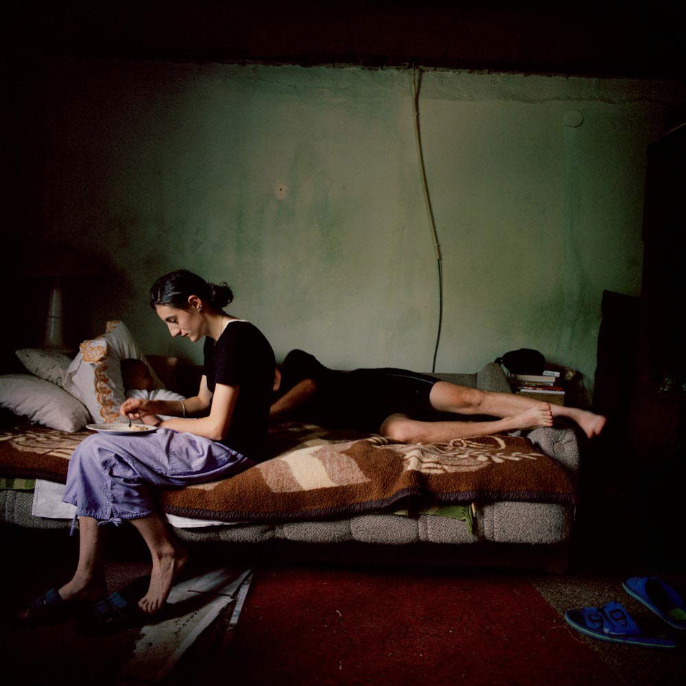 Ivor Prickett, Slavica Eremic nutre il suo bambino Nikola mentre suo marito Nebojsa dorme (2006, Jurga, Croazia /Fotografia dalla serie Returning Home – Croatia, Courtesy e © Ivor Prickett