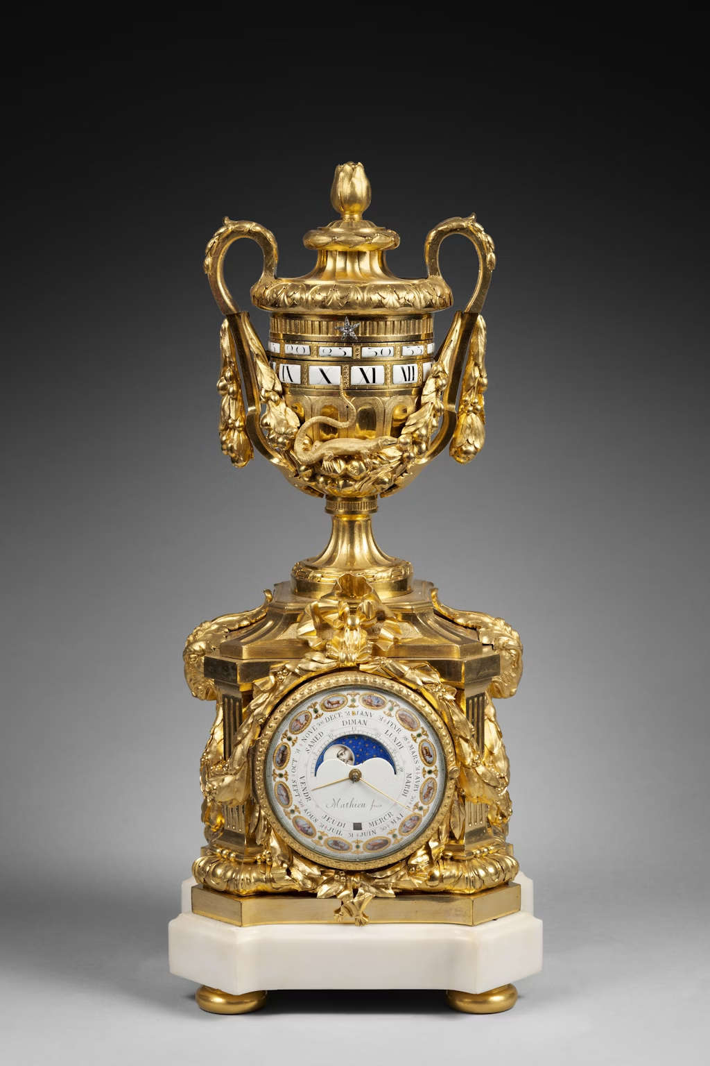 Claude Mathieu, Joseph Coteau and Robert Osmond, Rare vase-shaped clock with astronomical and lunar indications in matte gilded and burnished bronze (early Louis XVI period, c. 1774; bronze, enamel, Carrara marble, 56 x 25 x 21.5 cm).