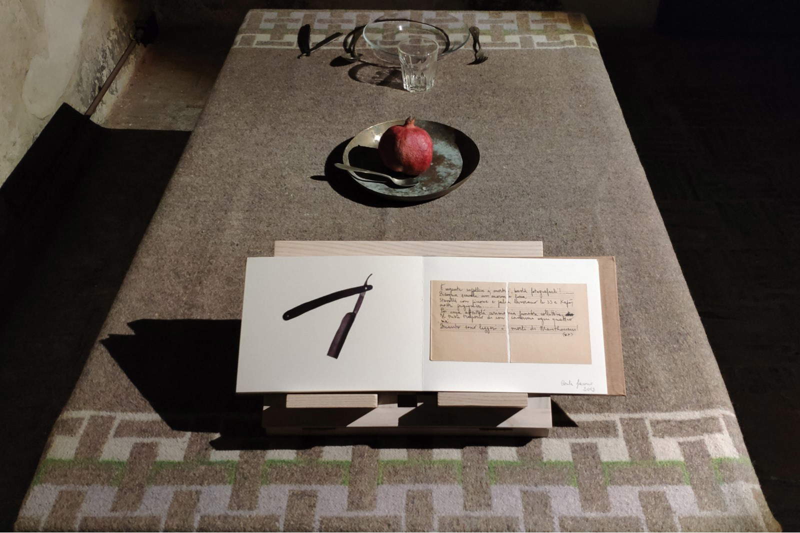 Carla Iacono, The Grey Zone (2019 ; installation : table, couverture militaire de la Seconde Guerre mondiale, verrerie, couverts vintage, pupitre en bois, grenade, livre d'artiste, dimensions variables, spécifique au site). Carla Iacono, The Grey Zone (2019 ; installation : table, couverture militaire de la Seconde Guerre mondiale, verrerie, couverts vintage, pupitre en bois, grenade, livre d'artiste, dimensions variables, spécifique au site).