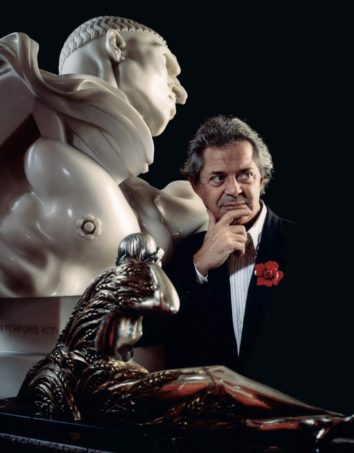 Franco Maria Ricci photographié avec la célèbre fleur de Bakélite à sa boutonnière et quelques œuvres du XXe siècle de sa collection, le Vir Temporis Acti de Wildt et une statuette Art déco.