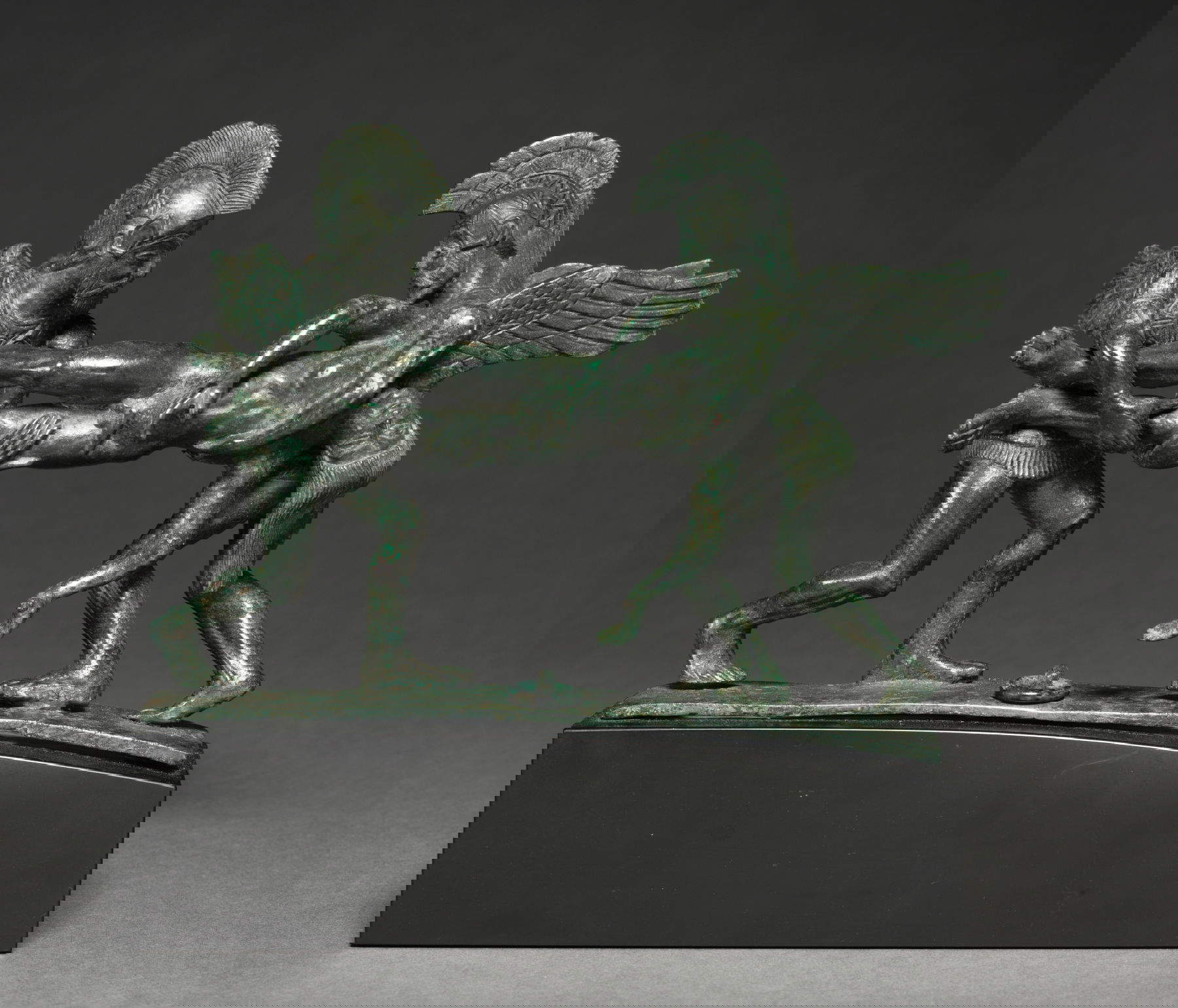 Manico per cista raffigurante Sonno (Hypnos) e Morte (Thanatos) mentre sorreggono il corpo di Sarpedon (400-375 a.C.; bronzo, con base 18,5 x 18,3 cm, senza base 14 x 17,4 cm; Cleveland, Cleveland Museum of Art)