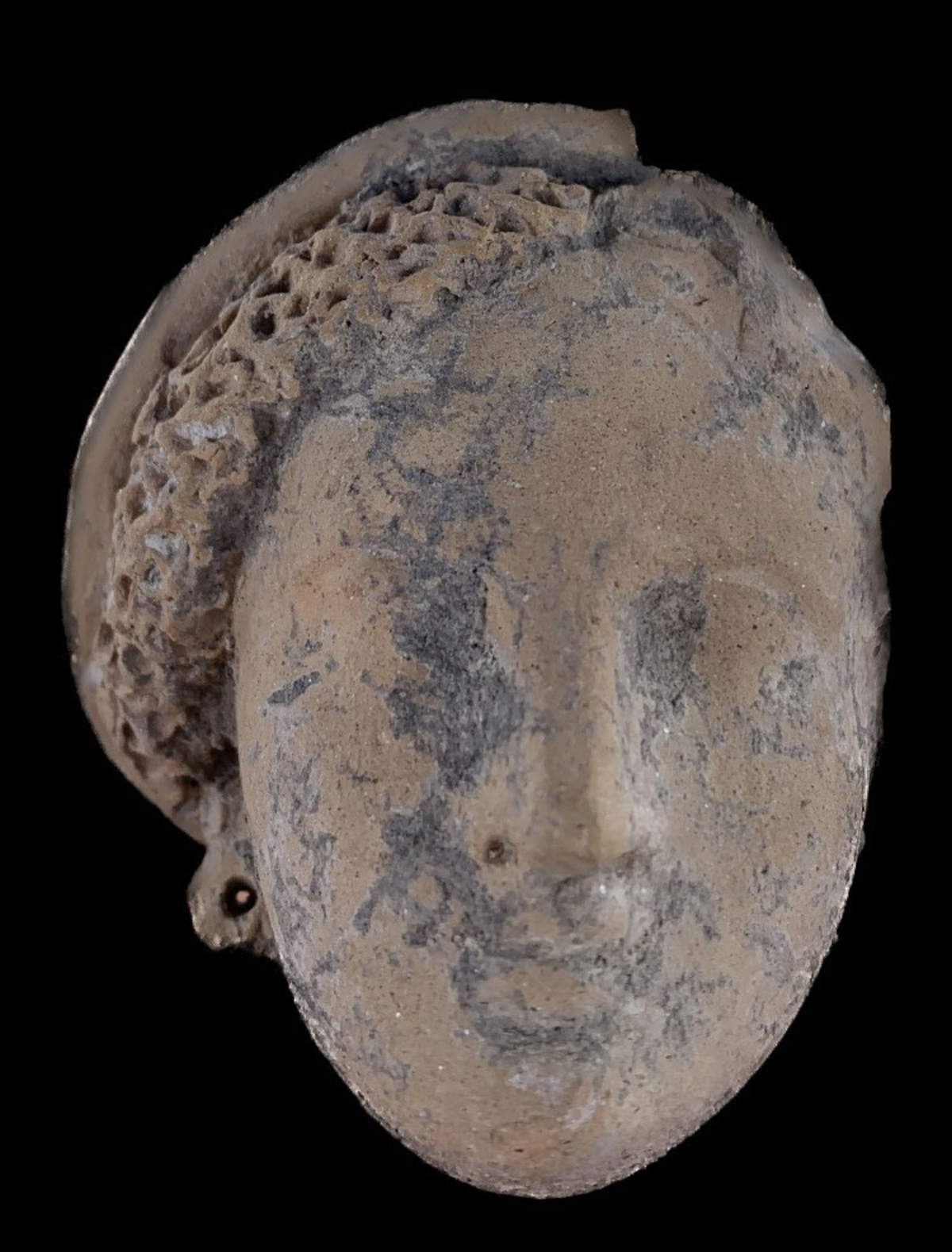 Testa di una figurina femminile con elaborato copricapo e orecchini