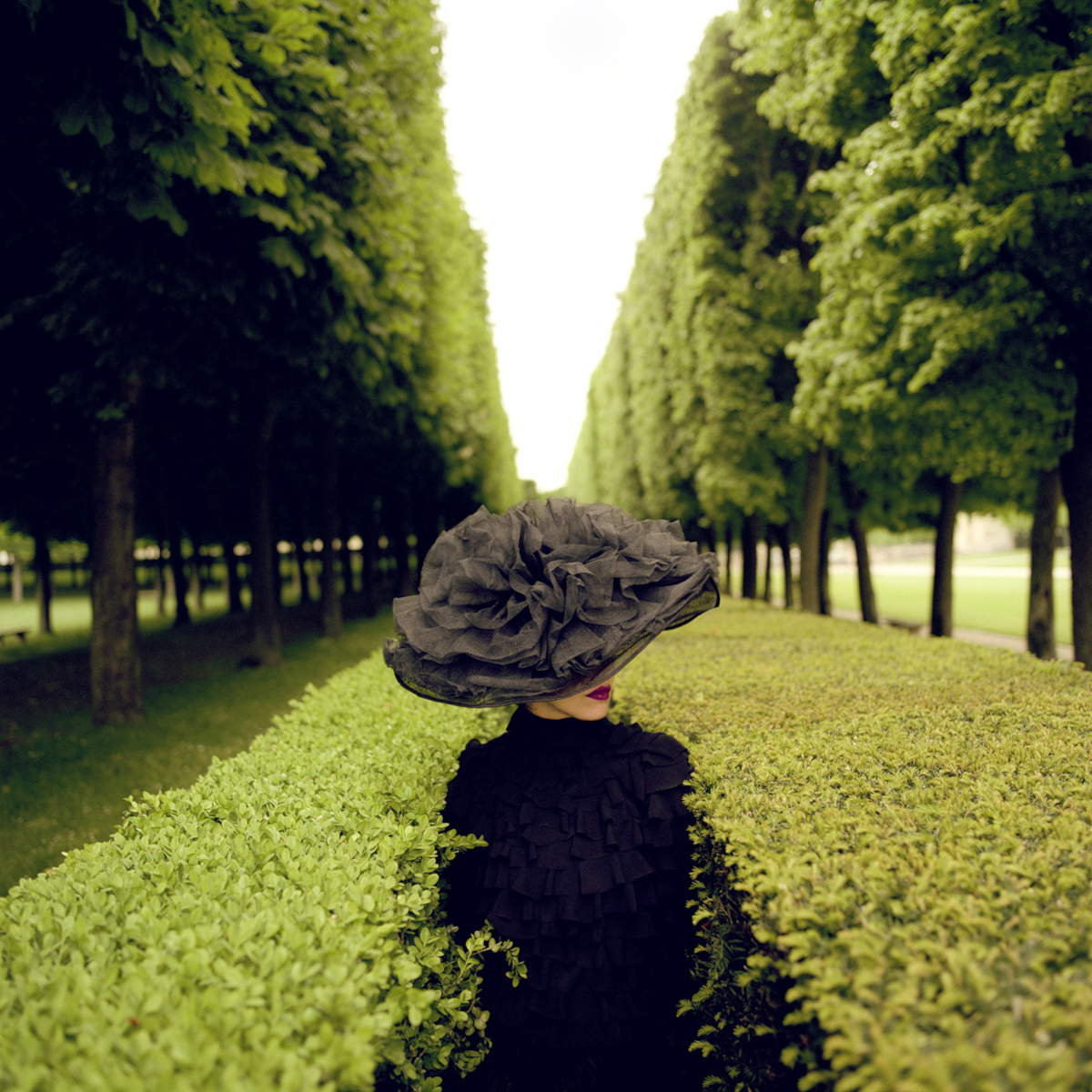 Woman with Hat between Hedges, Parc de Sceaux, France, 2004 &copy; Rodney Smith