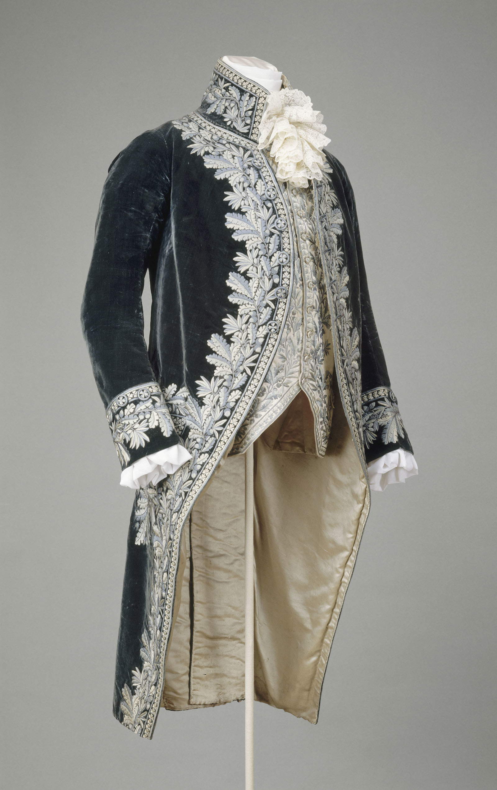 Isabey Jean-Baptiste, costume designer, Large uniform of a State Councilor: jacket and vest, c. 1804-1815. Jacket: dark blue silk velvet, satin stitch embroidery in various shades of blue-green silk with oak leaf motifs. Lining in ivory silk satin. Vest: ivory silk satin, polychrome silk thread embroidery, cotton canvas back. Closure with metal tab. Modern shirt and tie; Rueil-Malmaison, Mus&eacute;e national des ch&acirc;teaux de Malmaison et de Bois-Pr&eacute;au &copy; GrandPalaisRmn (Mus&eacute;e national des ch&acirc;teaux de Malmaison et de Bois-Pr&eacute;au). Photo by Daniel Arnaudet