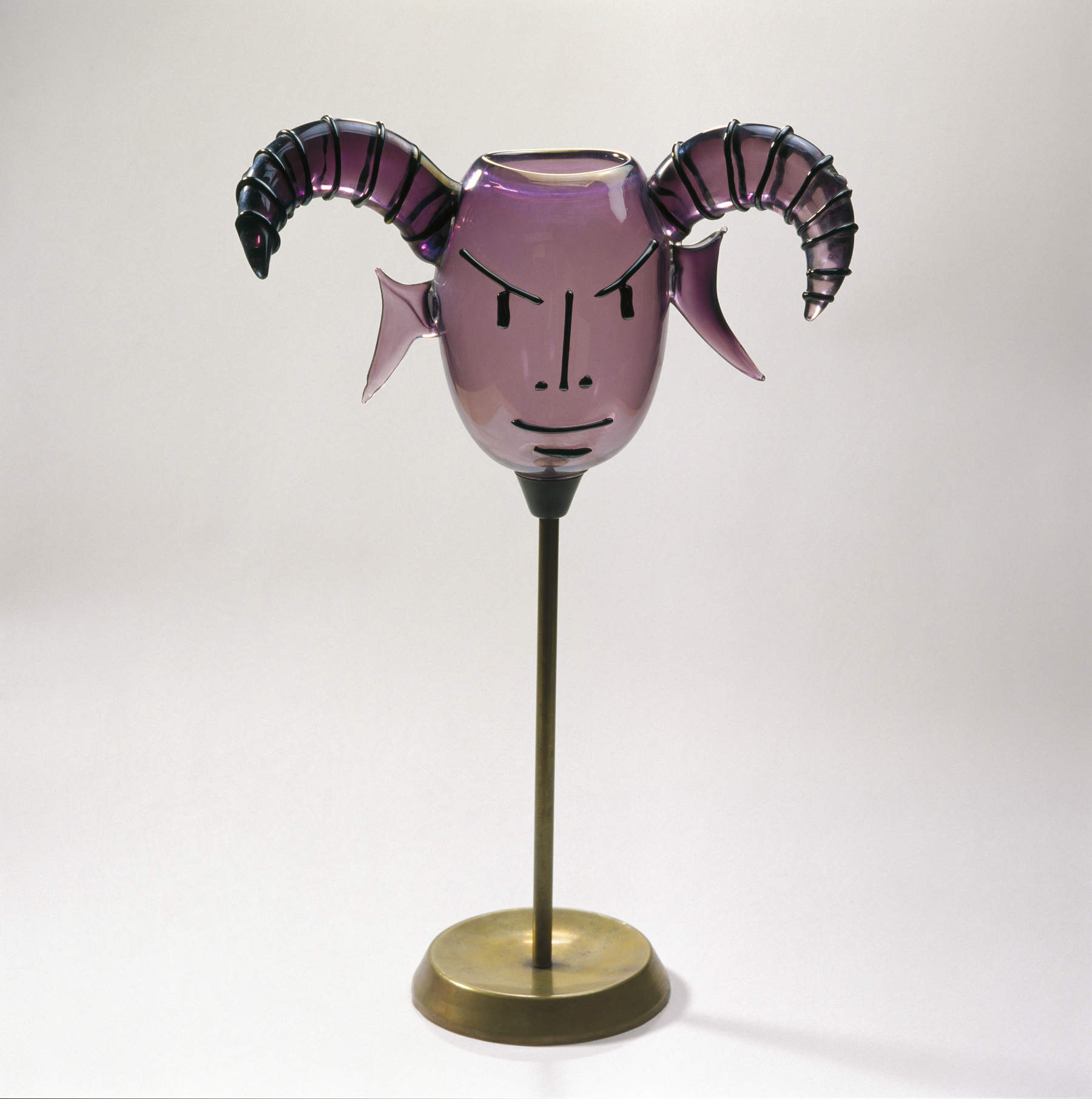 Jean Cocteau, Caprone (o Lucifero) (1962; Vetro ametista soffiato e modellato a caldo, particolari in vetro nero, supporto in metallo, 56 &times; 33 &times; &Oslash; 19 cm; Losanna, Mudac, Collection de la Ville de Lausanne) &copy; JEAN CLEMENT EUGENE MAR COCTEAU, by SIAE 2026