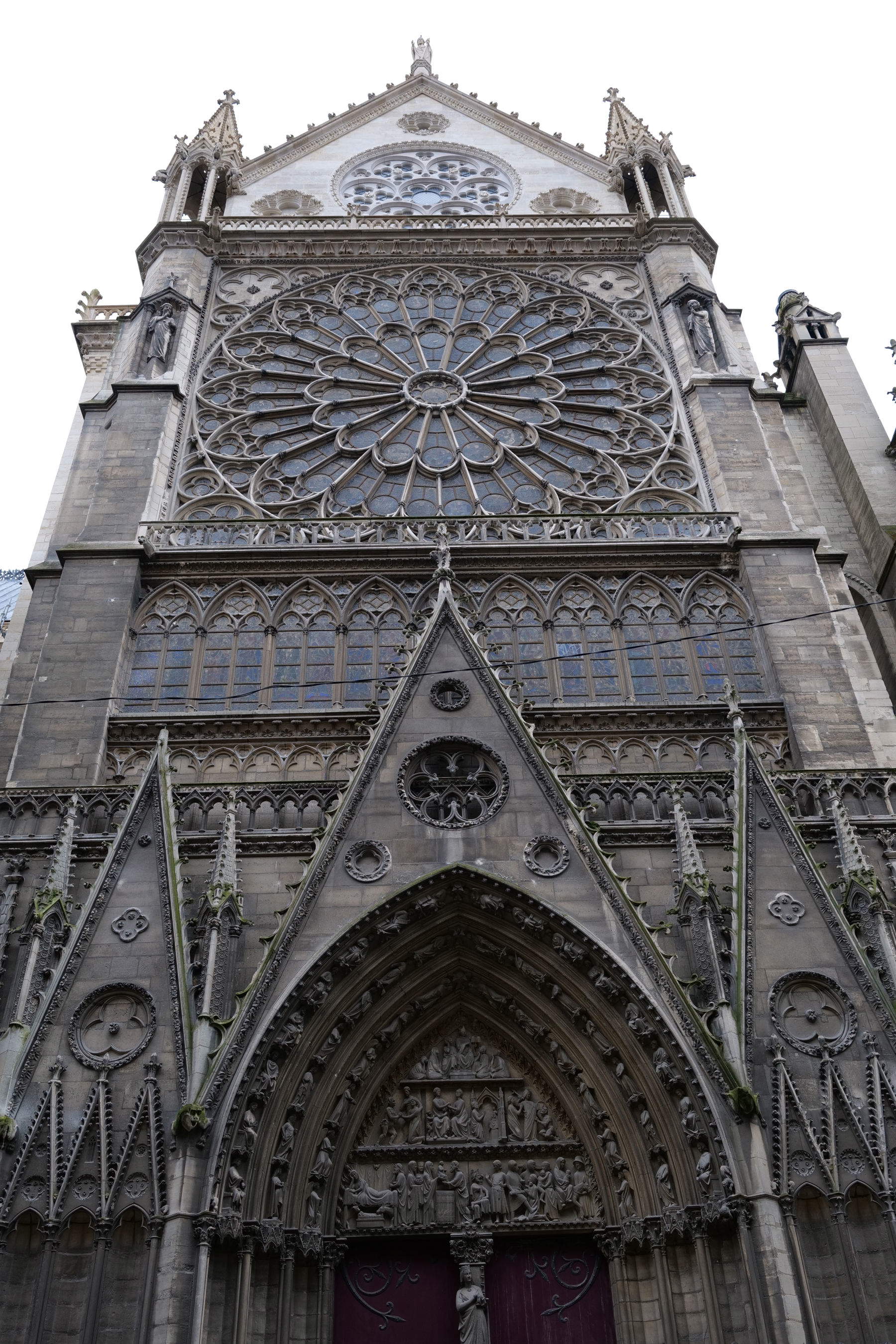 La fachada norte de la catedral de Notre-Dame de París y su portal fueron construidos a mediados del siglo XIII por Jean de Chelles. Oscurecidos por los efectos del paso del tiempo, contrastan con el tono claro del frontón, que ya ha sido completamente restaurado. Su restauración comenzará a lo largo de 2027. Romaric Toussaint &copy; Reb&acirc;tir Notre-Dame de París