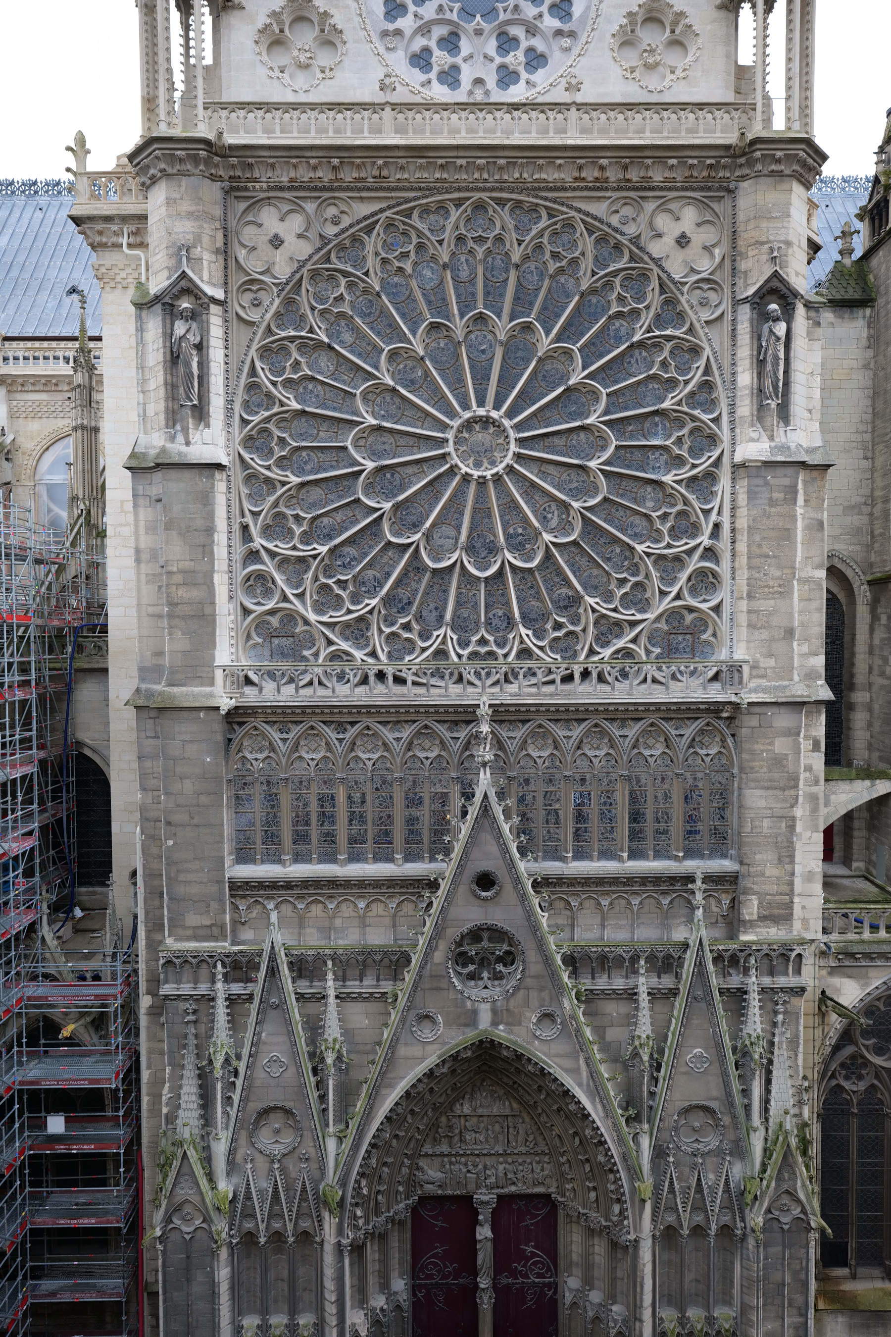 La fachada norte de la catedral de Notre-Dame de París y su portal fueron construidos a mediados del siglo XIII por Jean de Chelles. Oscurecidos por los efectos del paso del tiempo, contrastan con el tono claro del frontón, que ya ha sido completamente restaurado. Su restauración comenzará a lo largo de 2027. Romaric Toussaint &copy; Reb&acirc;tir Notre-Dame de París
