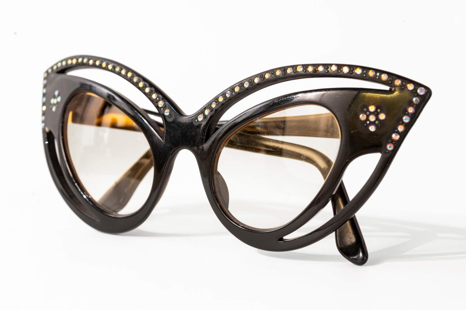 Between the 1960s and 1970s, the cat-eye shape evolved and was enhanced with new decorative elements, such as small rhinestones applied to the frame, along with amber-colored and gradient-tinted lenses. The Italian pair on display here exemplifies a particularly refined design aesthetic, transforming the eyewear into an elegant and striking accessory. Eyewear Museum Collection.