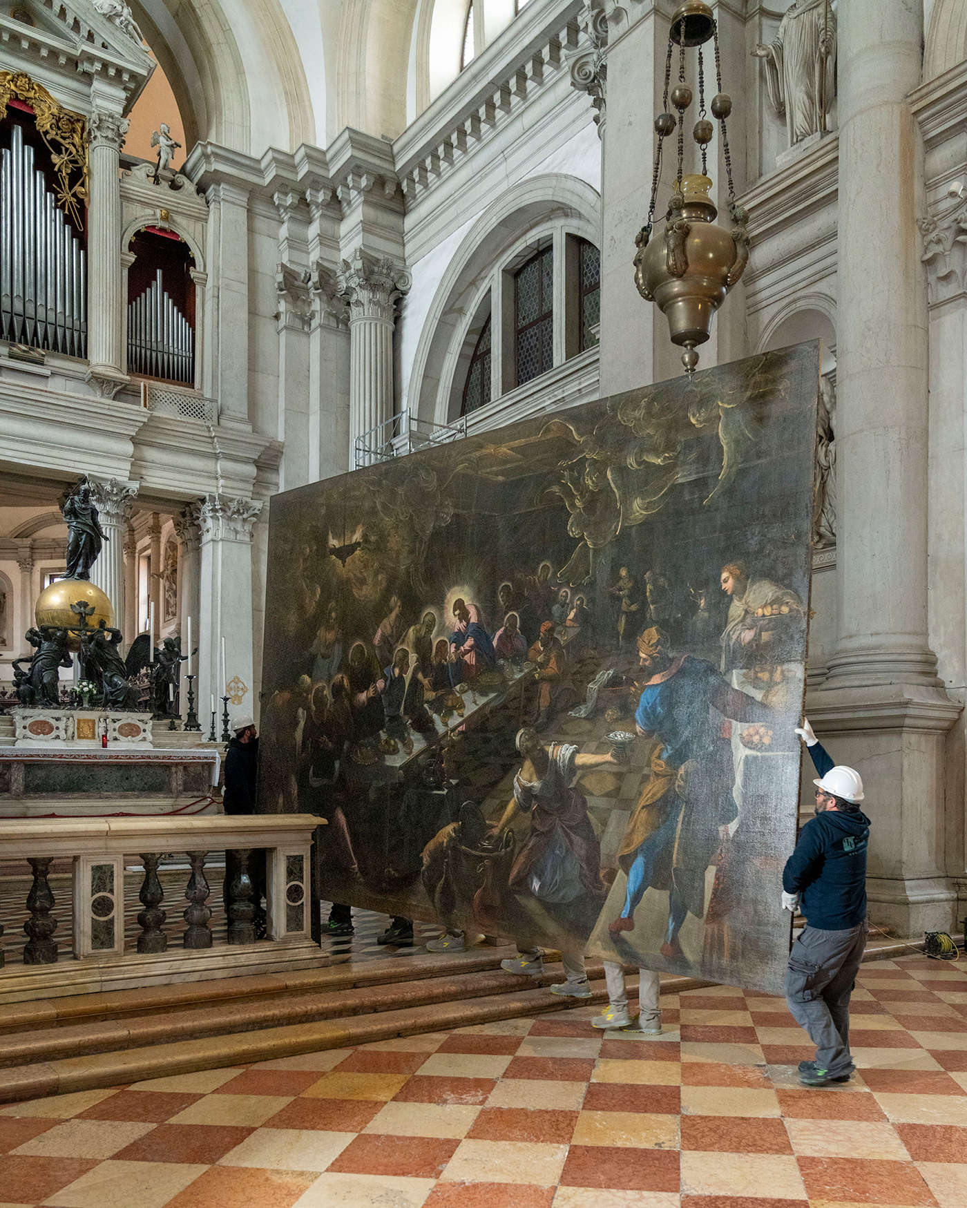 Addetti al restauro d'arte della ditta UniSVe ricollocano i dipinti restaurati nel presbiterio della basilica. Foto: Matteo De Fina