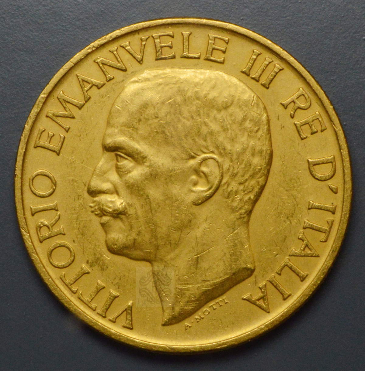 100 lire d&rsquo;oro del 1923, per commemorare il primo anniversario della Marcia su Roma. Dritto/ VITTORIO EMANVELE III RE D&rsquo;ITALIA. Testa nuda del re a sinistra; sotto il collo, il nome dell&rsquo;autore A(ttilio) MOTTI, OTTOBRE 1923, Roma Banca d'Italia - Palazzo Koch