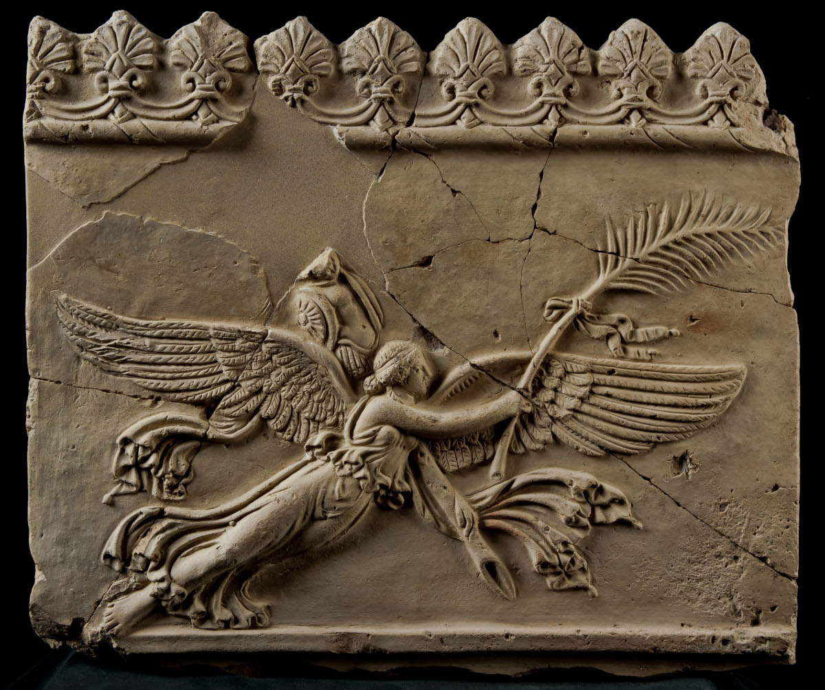 Lastra di coronamento raffigurante Vittoria in volo con palma e trofeo (terzo venticinquennio del I secolo a.C.; argilla rosata con rari inclusi di pozzolana; Roma, Museo Nazionale Romano - Palazzo Massimo)