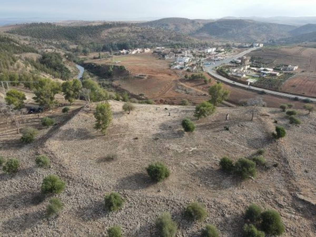 La zone du site d'Oued Beht délimitée par les ouvrages défensifs, avec le village d'A&iuml;t Siberne en arrière-plan (Photo : A. Garcia-Molsosa et T. Wilkinson, archives OBAP)